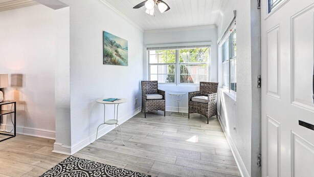 A hallway with a ceiling fan, a window, wicker chairs, a small table, and a patterned rug. - Pet-friendly Mt Dora Home w/ Fire Pit & Patio (Mount Dora)
