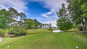 Un parcours de golf avec une pelouse bien entretenue, des arbres et un étang.
