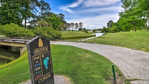 Un panneau indiquant un terrain de golf, avec un pont en arrière-plan.