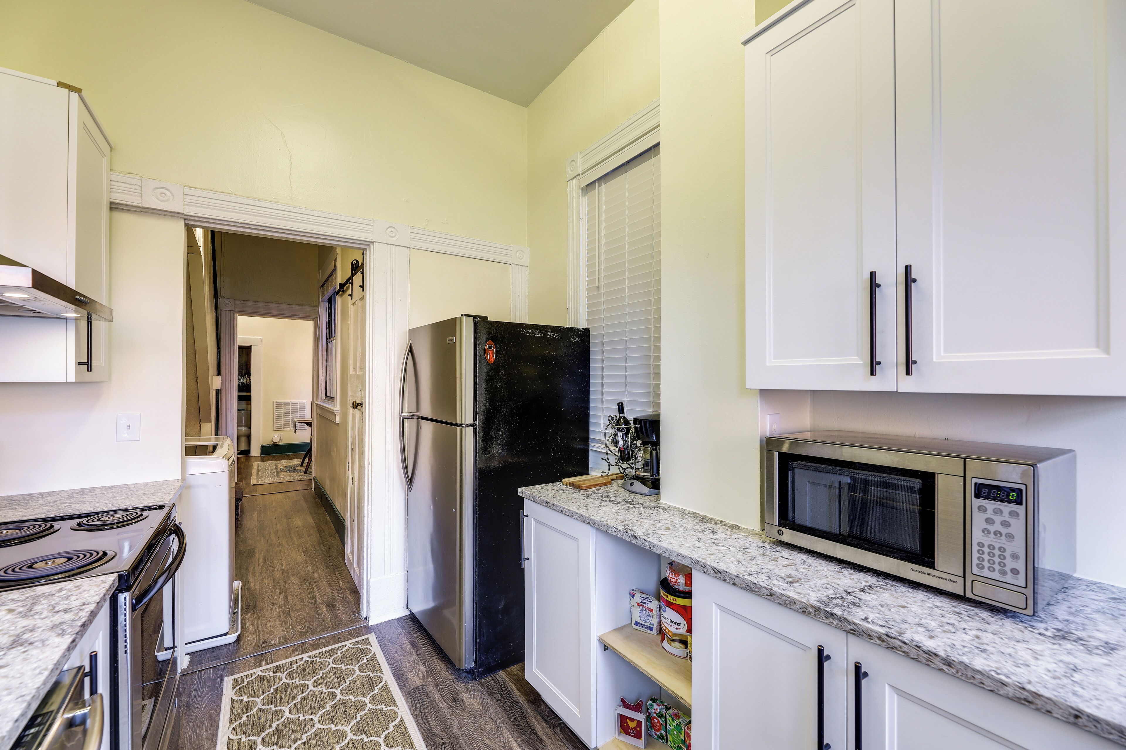 A kitchen with white cabinets, a black refrigerator, a microwave, and a stove.