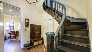 A staircase with a curved handrail, a wooden bench, a wall clock, and a door leading to another room. - Cincinnati Retreat w/ Patio & Grill! (Cincinnati)
