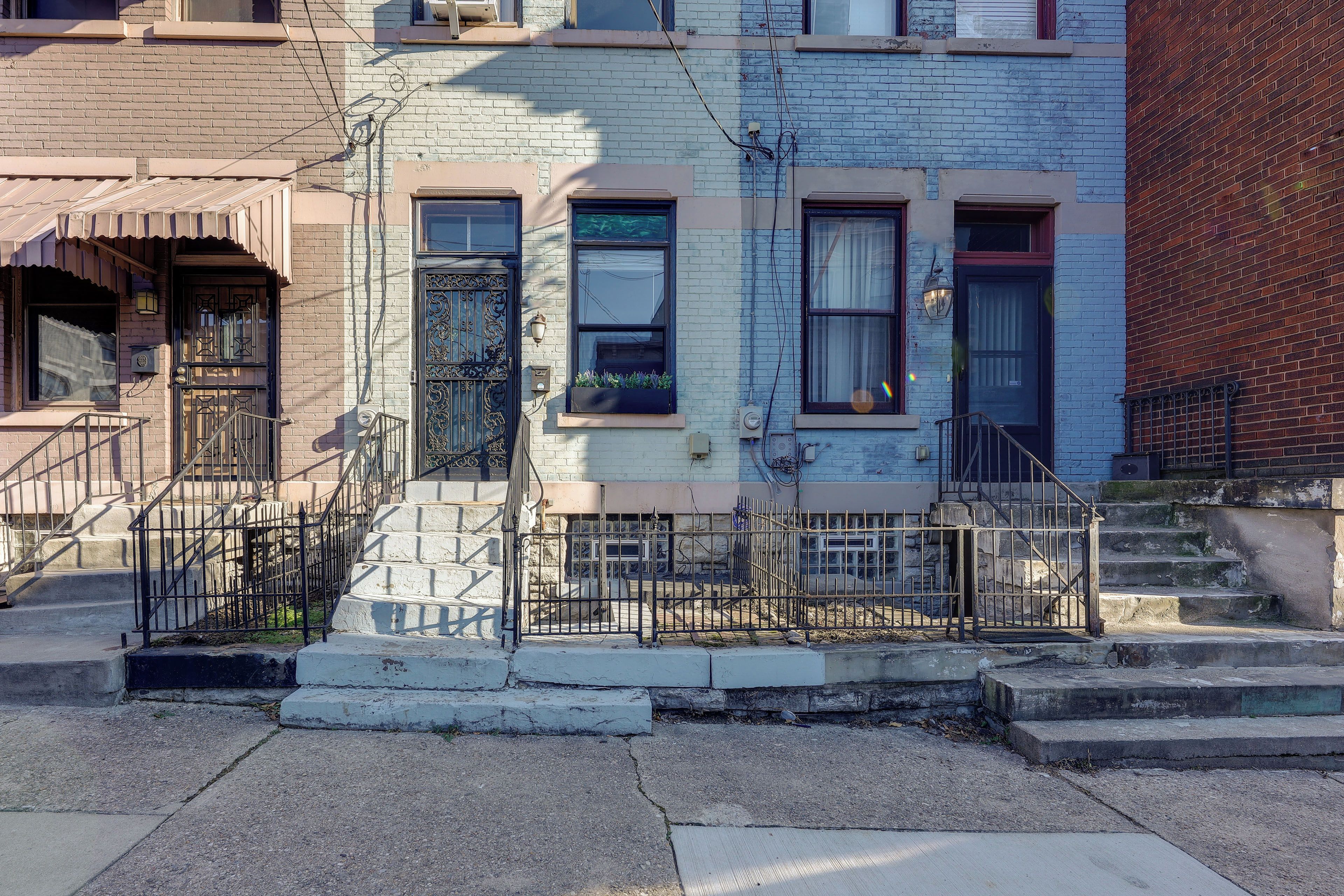 A row of townhouses with a front stoop, a metal fence, and a small garden area.