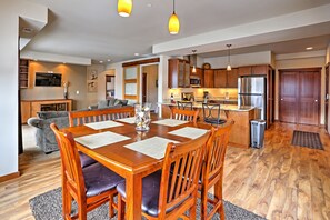 A spacious living area with a wooden dining table, comfortable seating, and a kitchen in the background. - Lake Chelan 'manson Bay' Condo w/ Pool Access! (Manson)