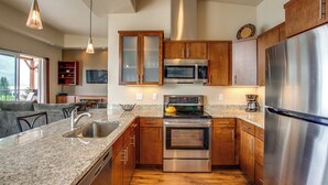 A modern kitchen with granite countertops, stainless steel appliances, wooden cabinets, and a large island with a sink. - Lake Chelan 'manson Bay' Condo w/ Pool Access! (Manson)