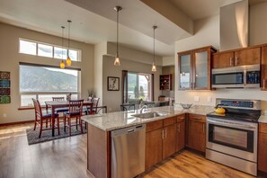 A spacious kitchen with wooden cabinets, stainless steel appliances, and a large island with a dishwasher. - Lake Chelan 'manson Bay' Condo w/ Pool Access! (Manson)