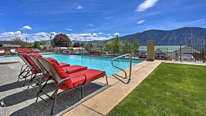 A swimming pool with red lounge chairs and a view of mountains. - Lake Chelan 'manson Bay' Condo w/ Pool Access! (Manson)
