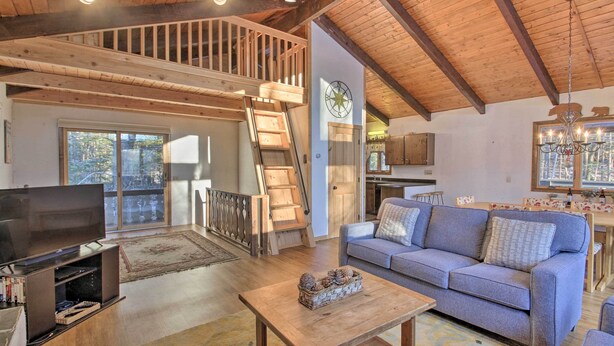 Ein geräumiger Wohnbereich mit einer Holztreppe, einem Sofa, einem Couchtisch und einem Fernseher.