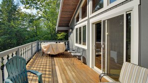 Eine Holzterrasse mit Gartenmöbeln, darunter Stühle und ein Tisch mit Tischdecke.
