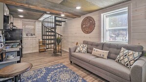 A cozy living room with a grey sofa, patterned cushions, a blue rug, a wooden coffee table, and a staircase leading to an upper level. - Peaceful Cookeville Cabin in Unique Setting (Cookeville)
