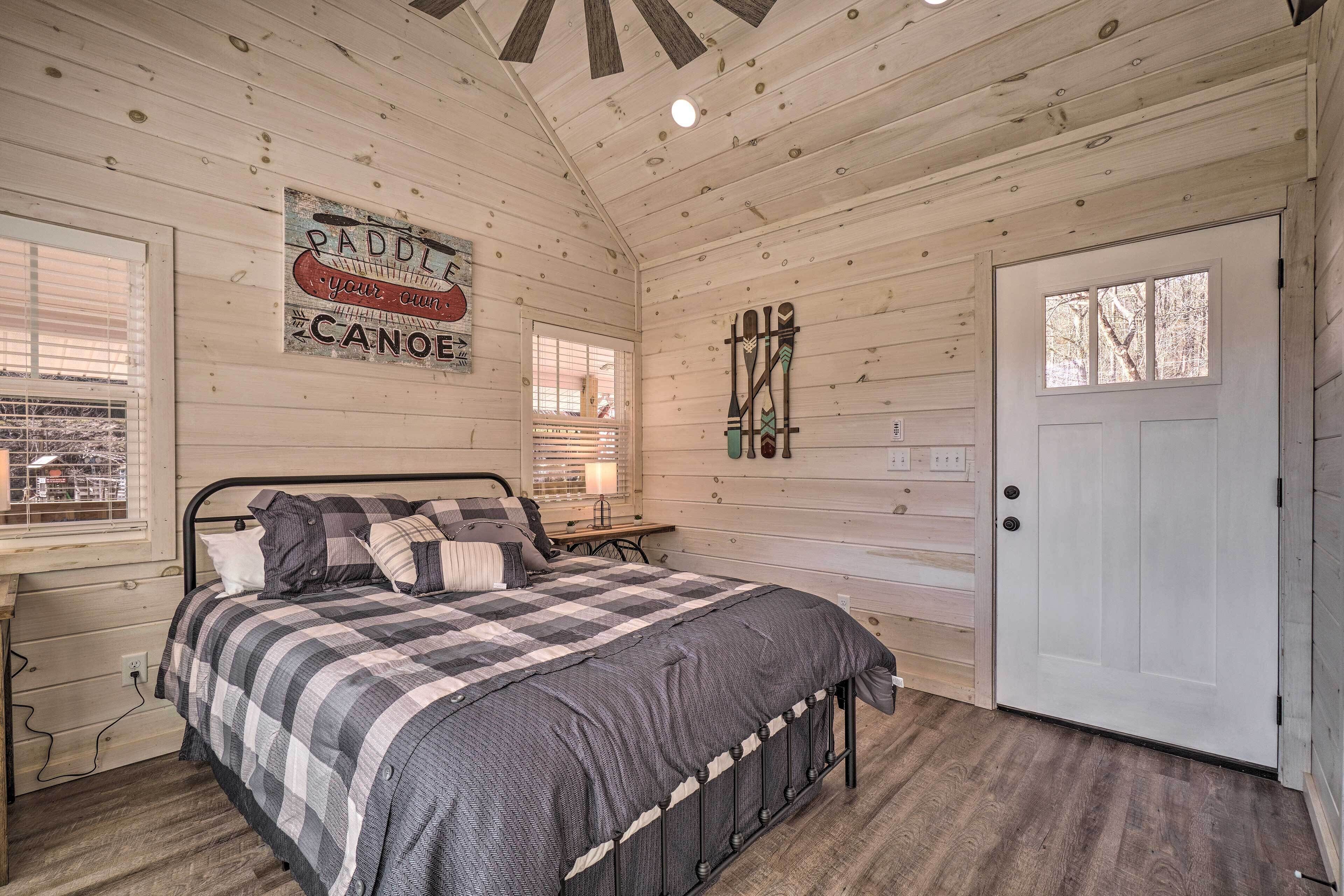 A bedroom with a bed, a door, a window, and a wall sign.