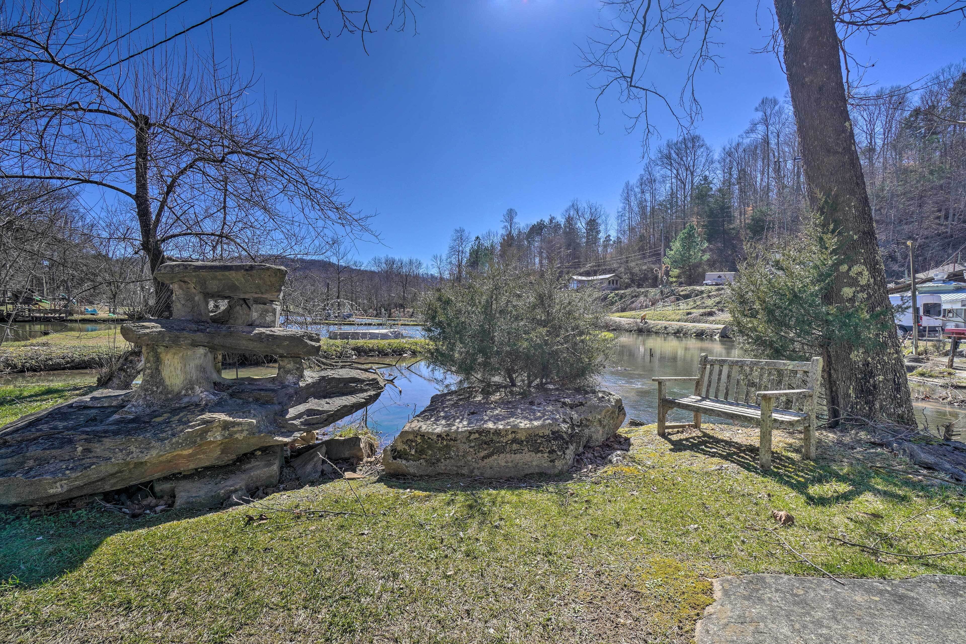 A park with a pond, a wooden bench, and a stone structure.