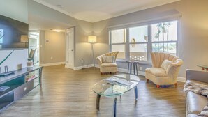 A spacious living room with hardwood flooring, a glass coffee table, two armchairs, and a sofa. - Fort Lauderdale Vacation Rental: Walk to Beach! (Fort Lauderdale)