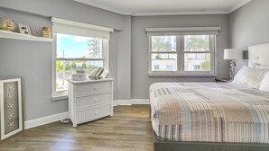 A bedroom with a large bed, two windows, a dresser, and a framed picture on the wall. - Fort Lauderdale Vacation Rental: Walk to Beach! (Fort Lauderdale)