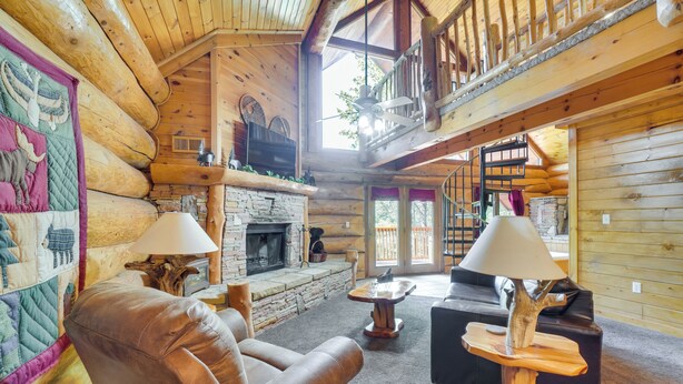 A log cabin interior with a fireplace, leather sofa, and a balcony. - Gatlinburg Vacation Rental w/ Hot Tub & Game Room! (Gatlinburg)