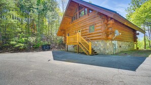 A log cabin with a stone foundation, a wooden deck, and a staircase leading to a balcony. - Gatlinburg Vacation Rental w/ Hot Tub & Game Room! (Gatlinburg)