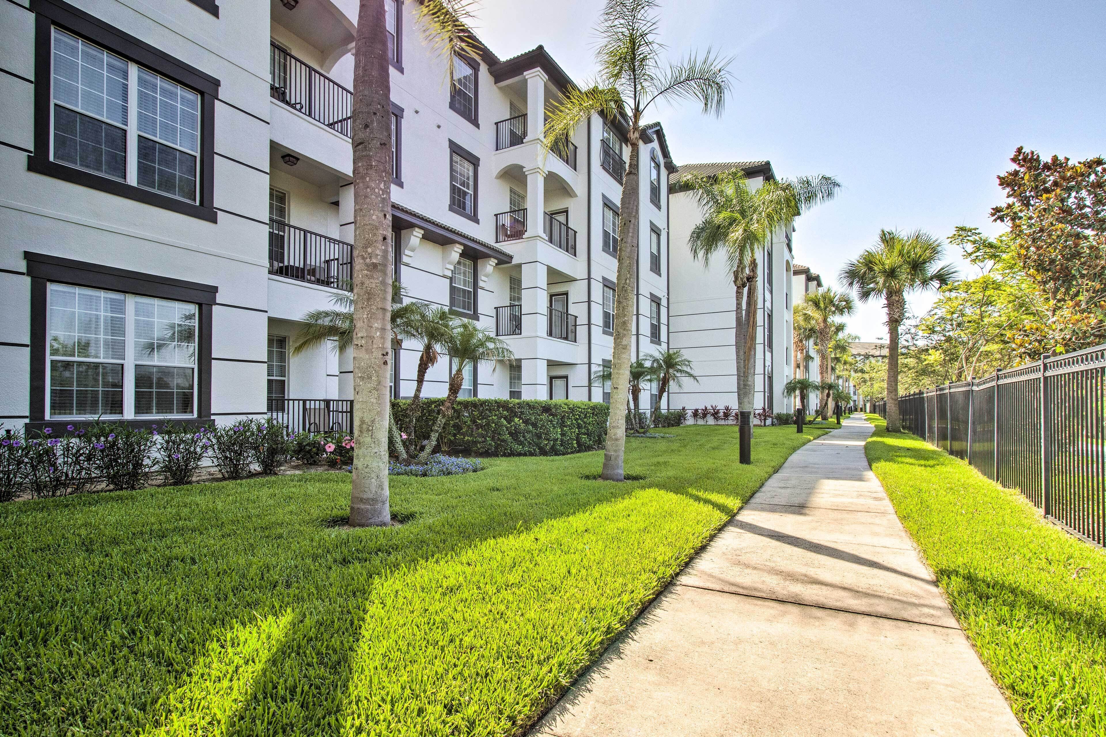 A multi-story building with balconies, a well-maintained lawn, and a sidewalk.