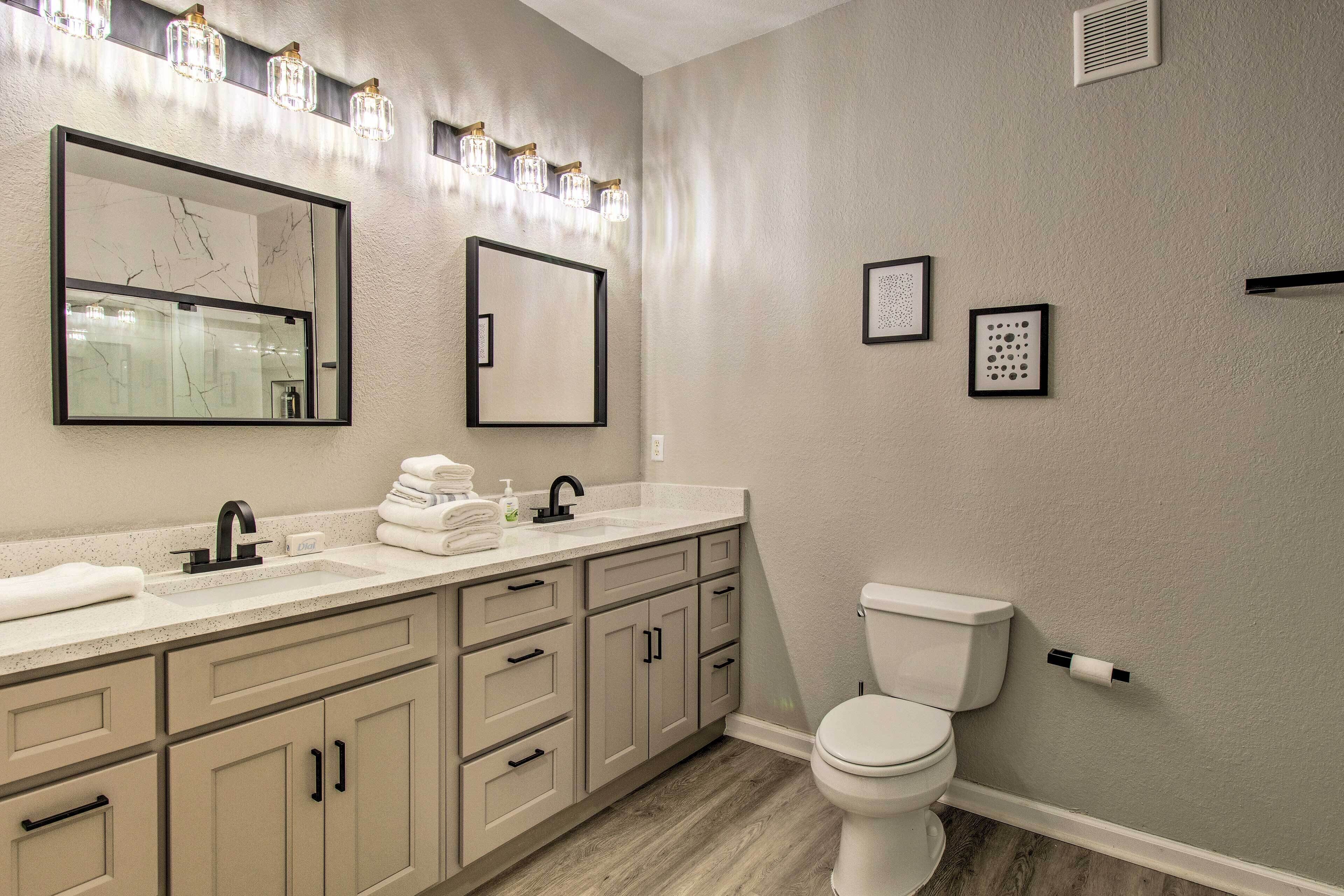 A bathroom with a white sink, a mirror, and a toilet. There are cabinets and a towel rack.