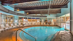 A large indoor swimming pool with clear glass walls, lounge chairs, and a tiled floor. - The Terrace at Pelican Beach Resort: View + Pool! (Destin)