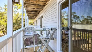 A covered porch with a table and chairs, a wooden deck, and a view of trees. - 'breezy Heights' Townhome < 1 Mi to Beach (Pensacola)