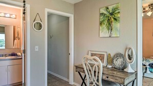 A dining area with a wooden table, white chairs, and a wall-mounted mirror. - 'breezy Heights' Townhome < 1 Mi to Beach (Pensacola)