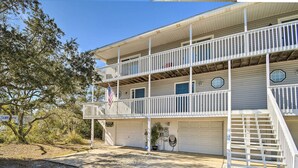 A two-story building with a balcony, a garage, and a flag. - 'breezy Heights' Townhome < 1 Mi to Beach (Pensacola)