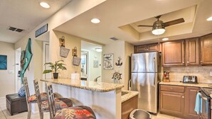 Una cocina con una isla central, electrodomésticos de acero inoxidable, armarios de madera y un ventilador de techo.