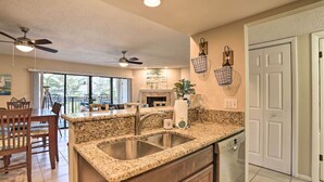 Una cocina con encimeras de granito, pileta de acero inoxidable y ventilador de techo.