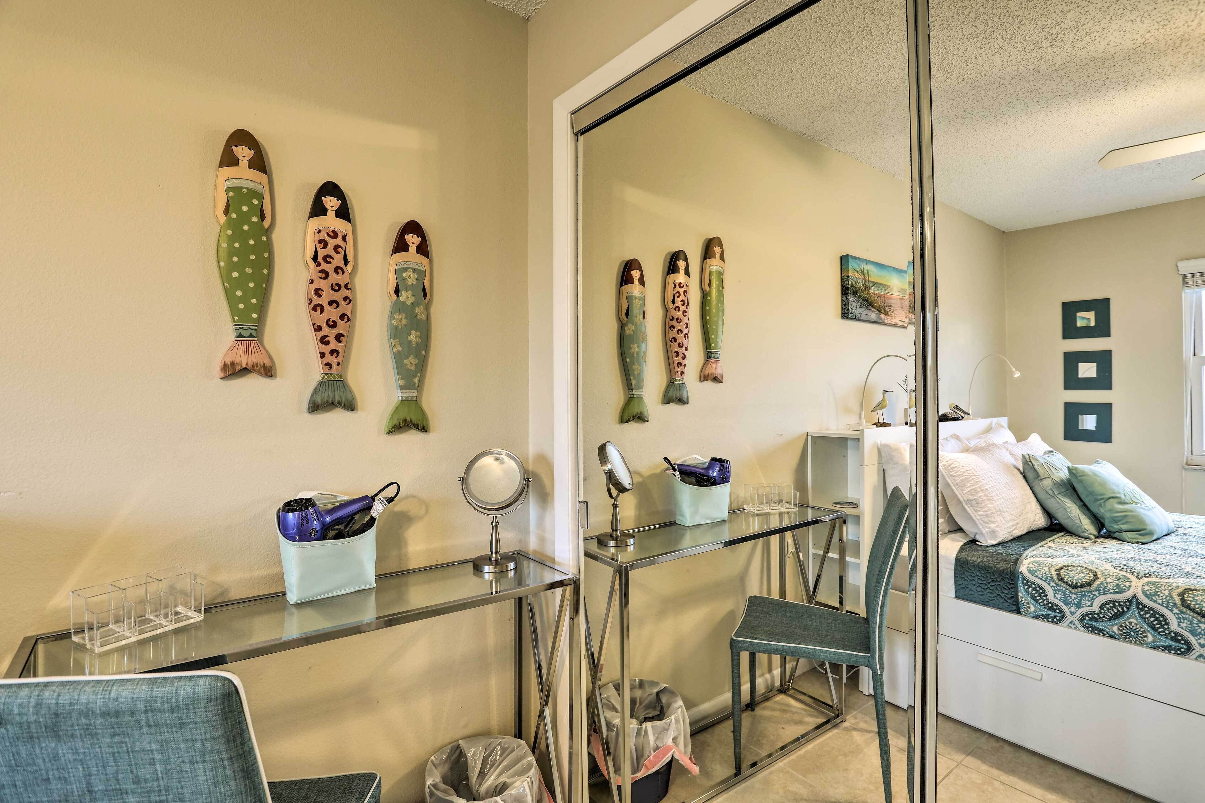 Une pièce comprenant un bureau en verre, une chaise, un lit avec une couvre-lit à motifs et des décorations murales en forme de poisson.