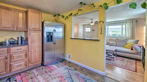 Una cocina con armarios de madera, un refrigerador de acero inoxidable y una alfombra colorida.