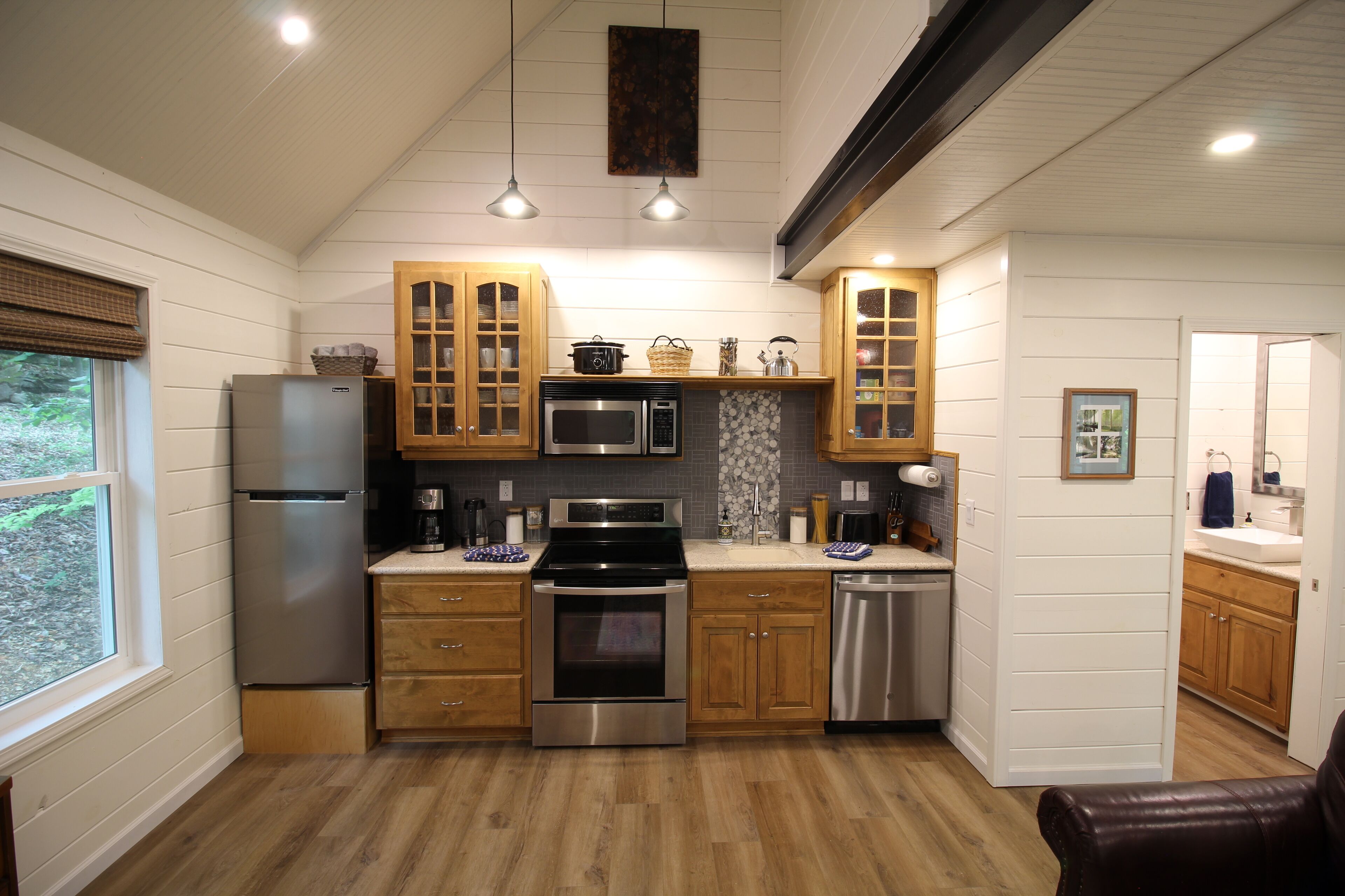 A modern kitchen with wooden cabinets, stainless steel appliances, and a view of the outdoors.