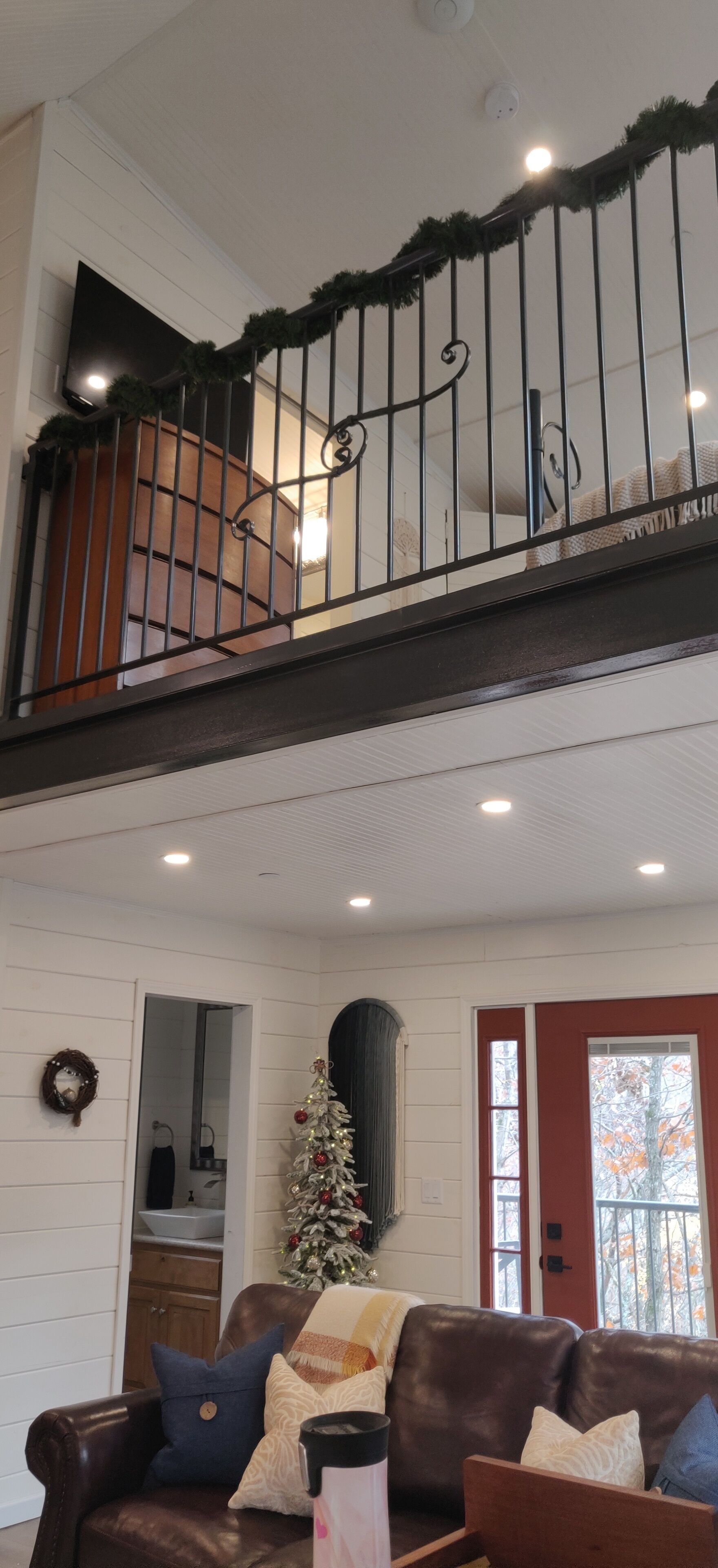 A two-story house with a staircase, a Christmas tree, and a brown leather couch.