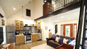 Una cocina amplia con electrodomésticos modernos, un comedor con mesa de madera y una sala de estar acogedora con sofá de cuero marrón.