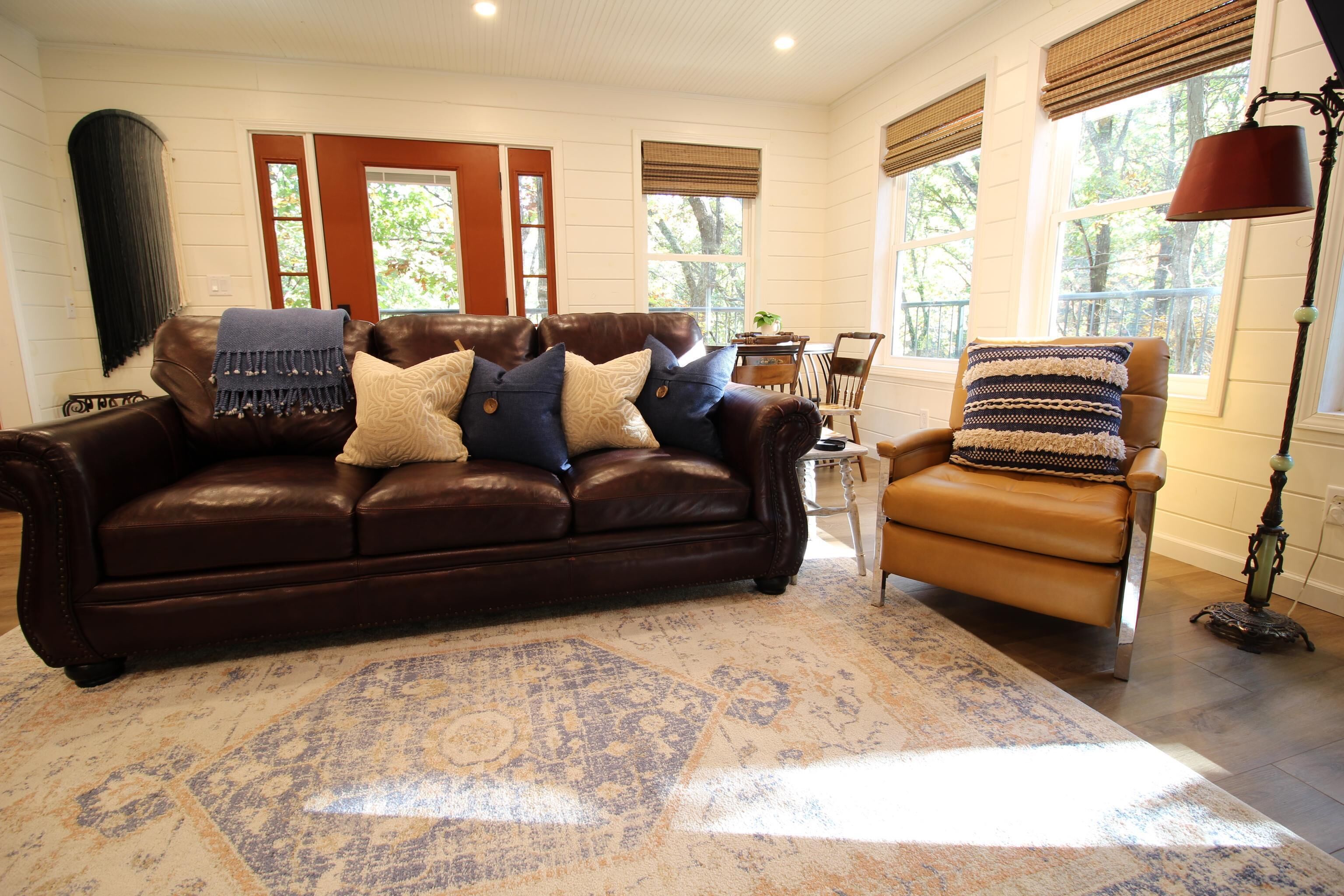 A cozy living room with a brown leather sofa, a patterned rug, and a tan armchair.
