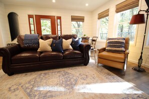 A cozy living room with a brown leather sofa, a patterned rug, and a tan armchair.