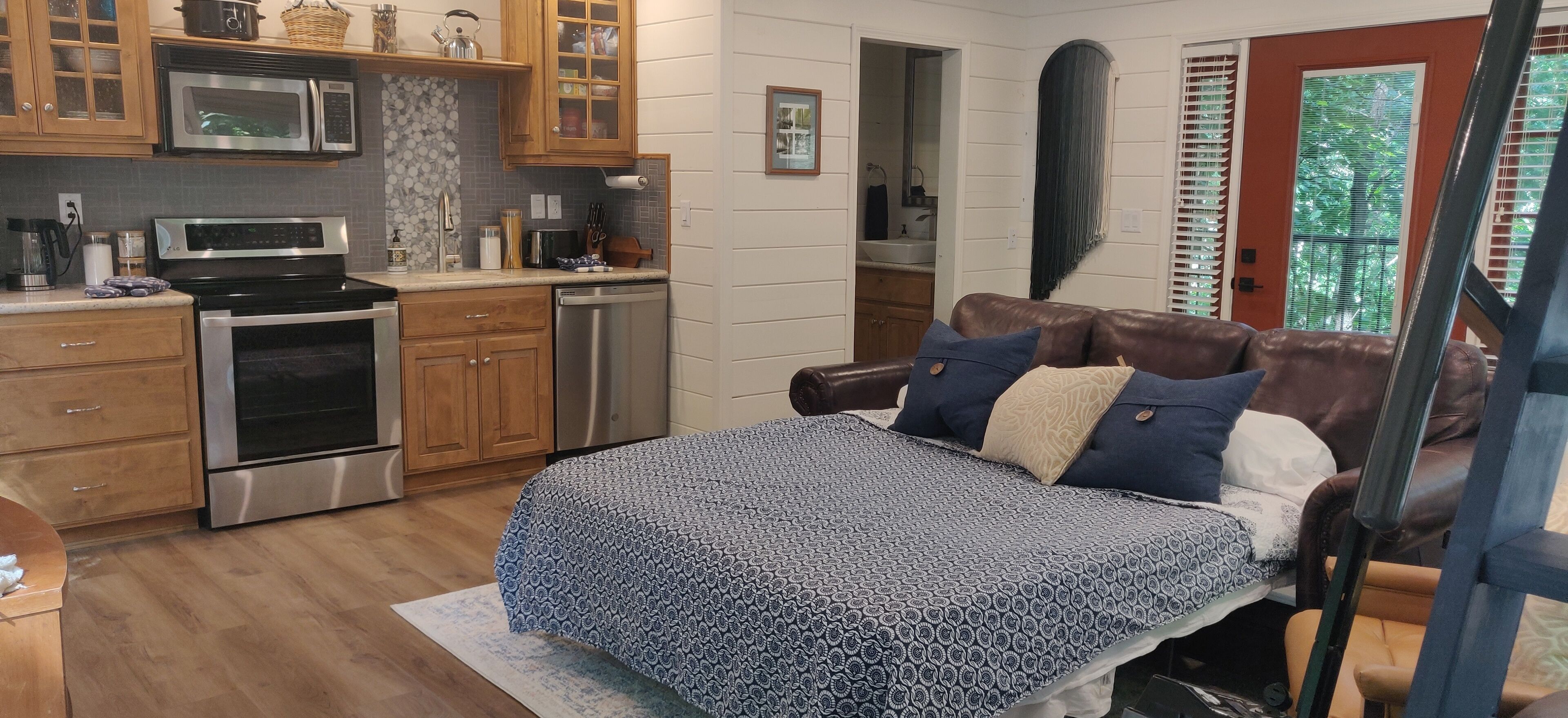 A bedroom with a bed, a dresser, a nightstand, and a window with blinds.