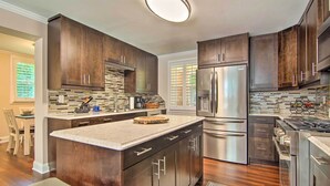 Una cocina moderna con armarios de madera oscura, electrodomésticos de acero inoxidable y una isla grande con encimera de mármol.