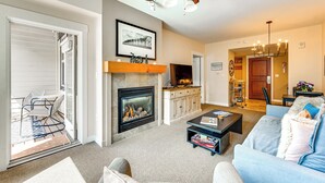 A living room with a fireplace, a ceiling fan, a television, and a sofa.