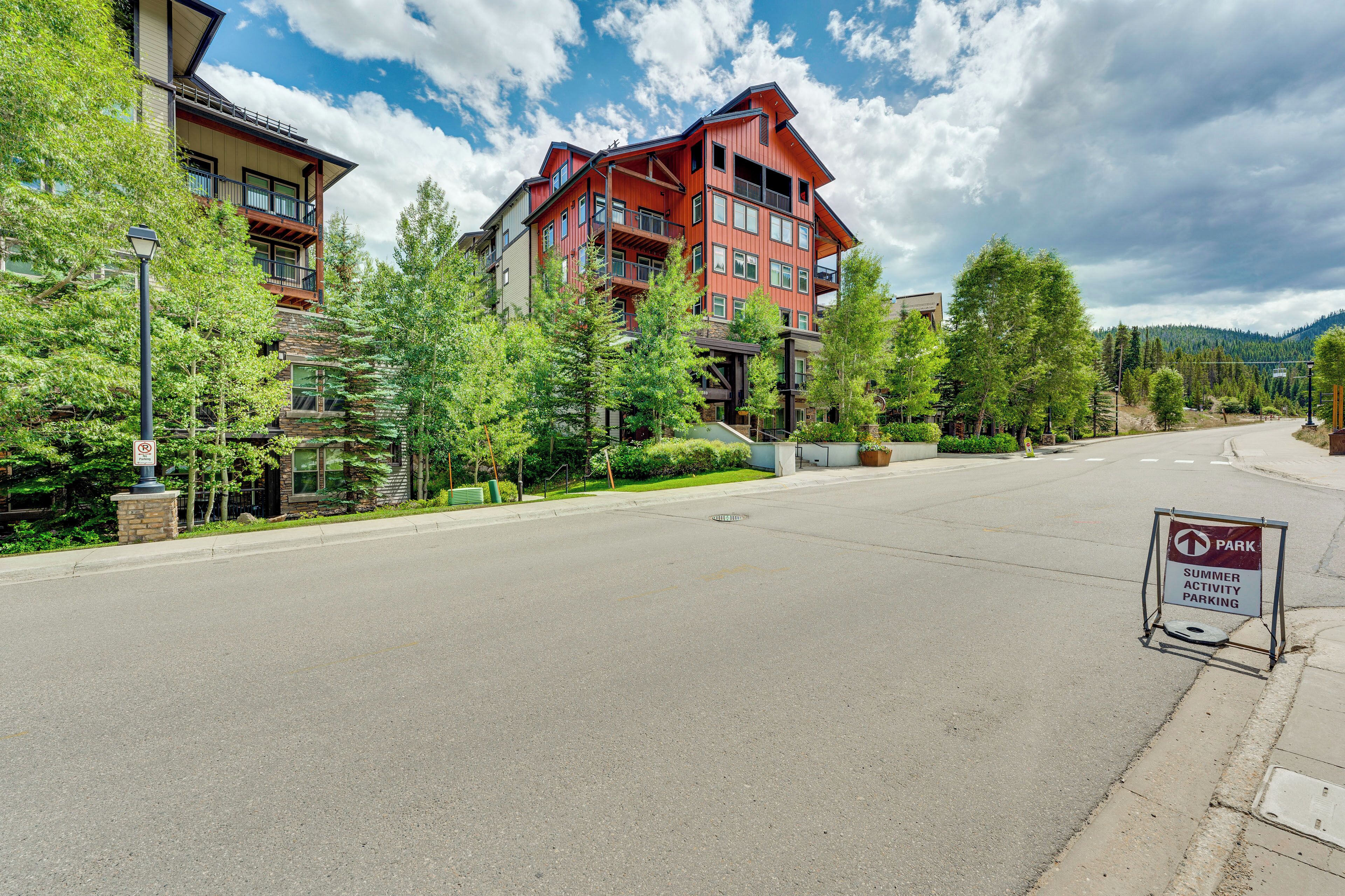 A multi-story building with a red facade, surrounded by trees and a clear sky.
