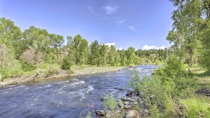 A river flowing through a forested area with rocks and vegetation along the banks. - 'the River Home' Cabin w/ Yard: Near Wolf Creek! (Pagosa Springs)