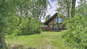 A modern wooden cabin with large windows, surrounded by lush greenery. - 'the River Home' Cabin w/ Yard: Near Wolf Creek! (Pagosa Springs)