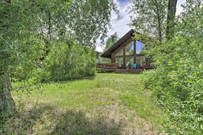 Une cabane moderne en bois, dotée de grandes fenêtres et entourée d’une végétation luxuriante.