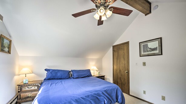 Un dormitorio con una cama grande, dos mesitas de noche con lámparas, un ventilador de techo y una puerta.