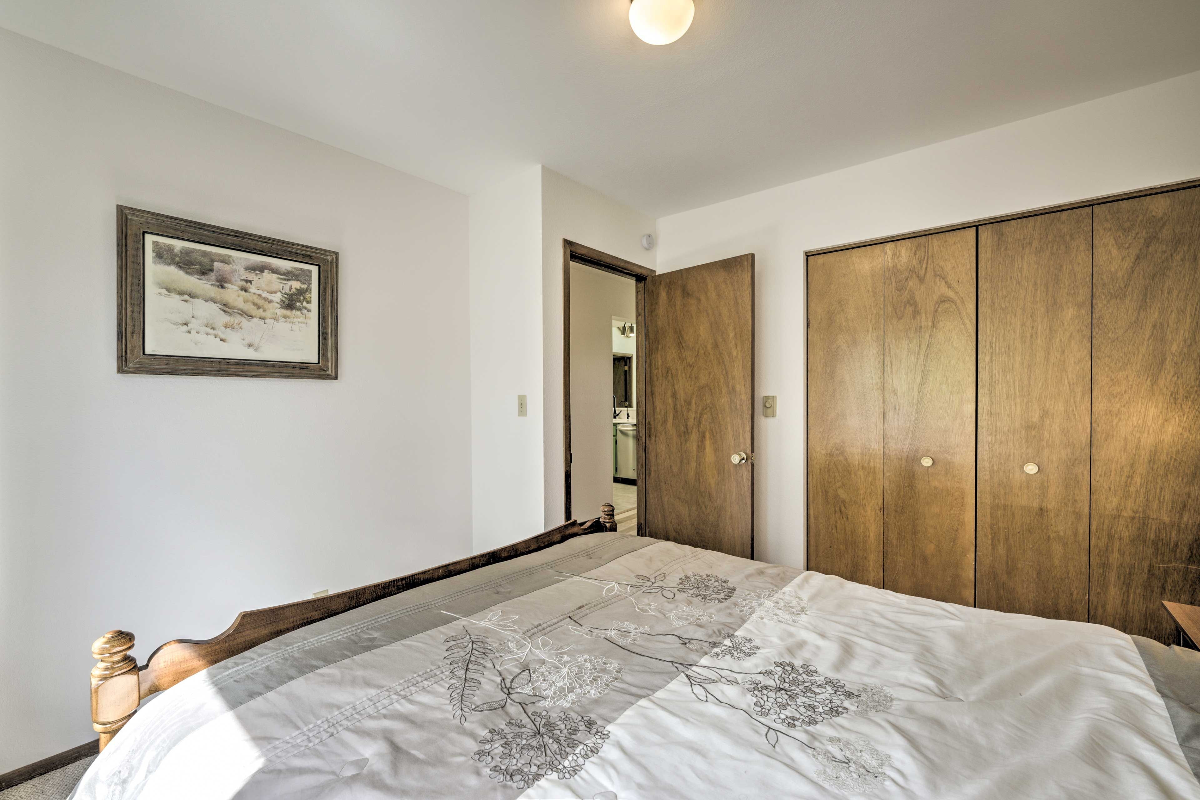 Ein Schlafzimmer mit einem hölzernen Bett, einem großen Kleiderschrank und einem gerahmten Bild an der Wand.