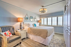 A bedroom with a bed, nightstand, chair, and large windows. - PCB Beachfront 'coastal Abode' at Pinnacle Port! (Panama City Beach)
