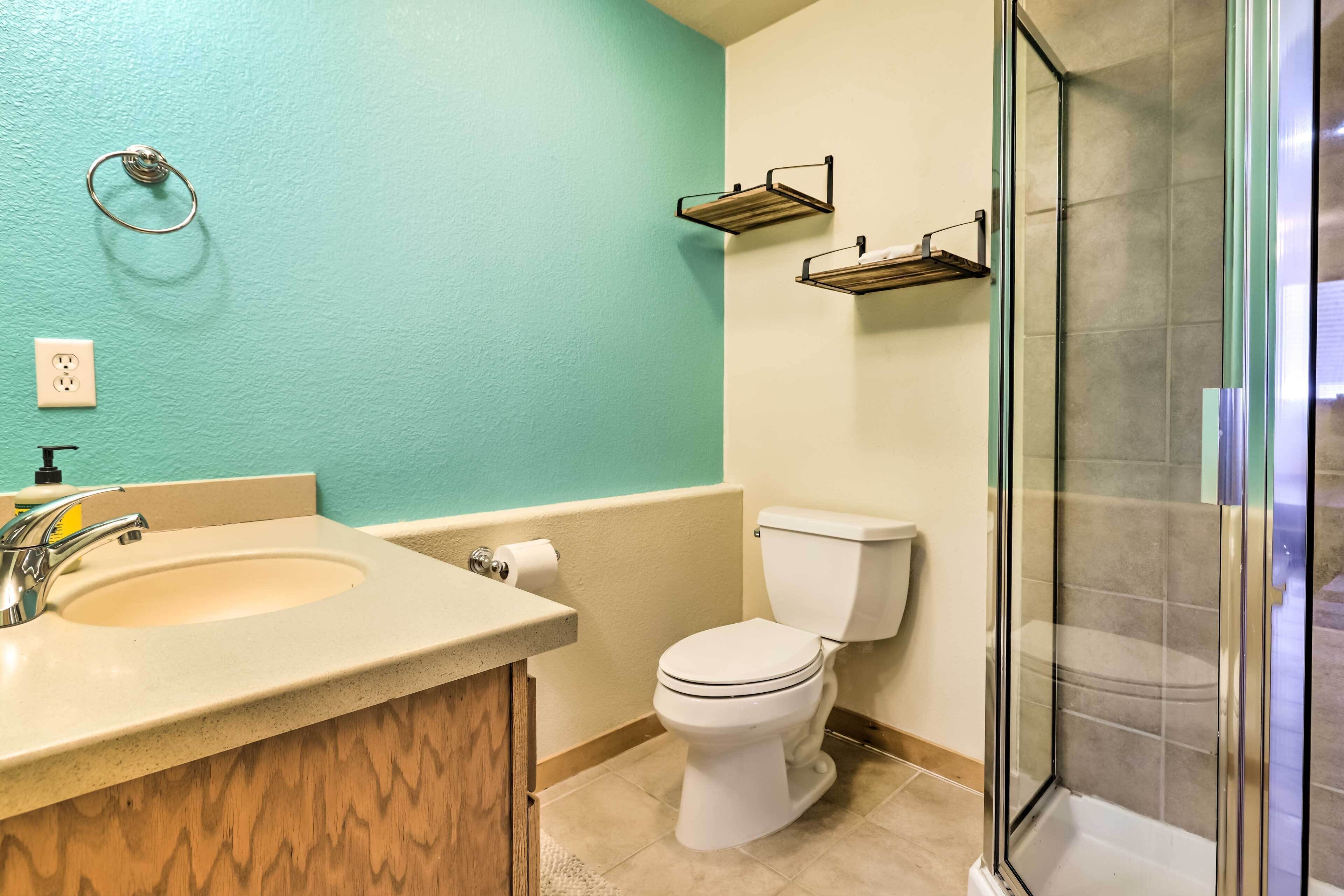 A bathroom with a sink, toilet, and glass shower enclosure.