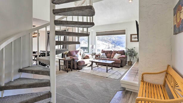 A spacious living area with a staircase, a wooden bench, and a view of the outdoors. - Walkable Winter Park Condo ~ 4 Mi to Slopes! (Winter Park)