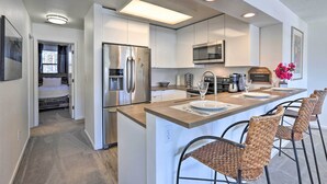 A modern kitchen with stainless steel appliances, a central island with bar seating, and a dining area with a large window. - Walkable Winter Park Condo ~ 4 Mi to Slopes! (Winter Park)