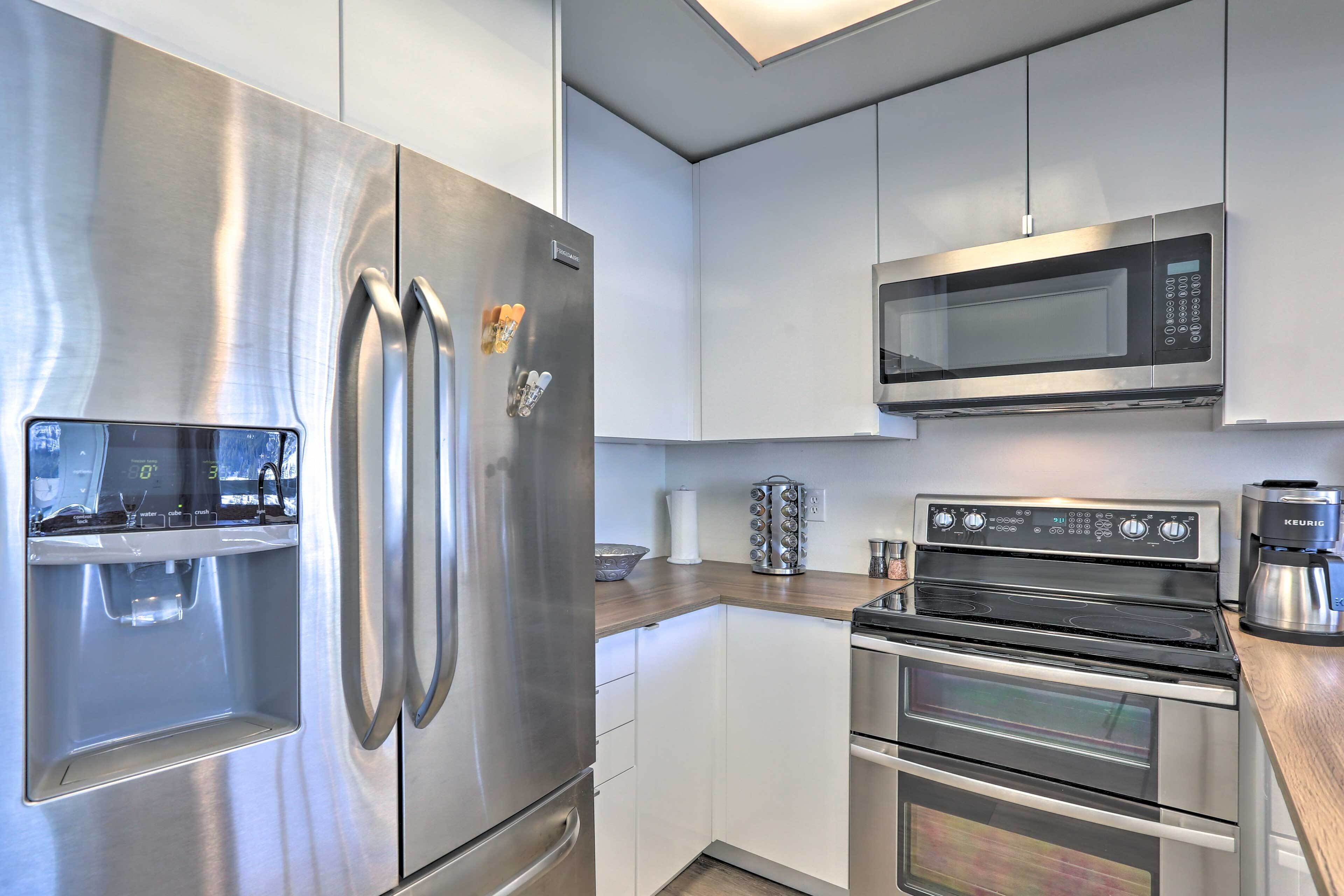 A modern kitchen with stainless steel appliances, including a refrigerator, microwave, and oven.