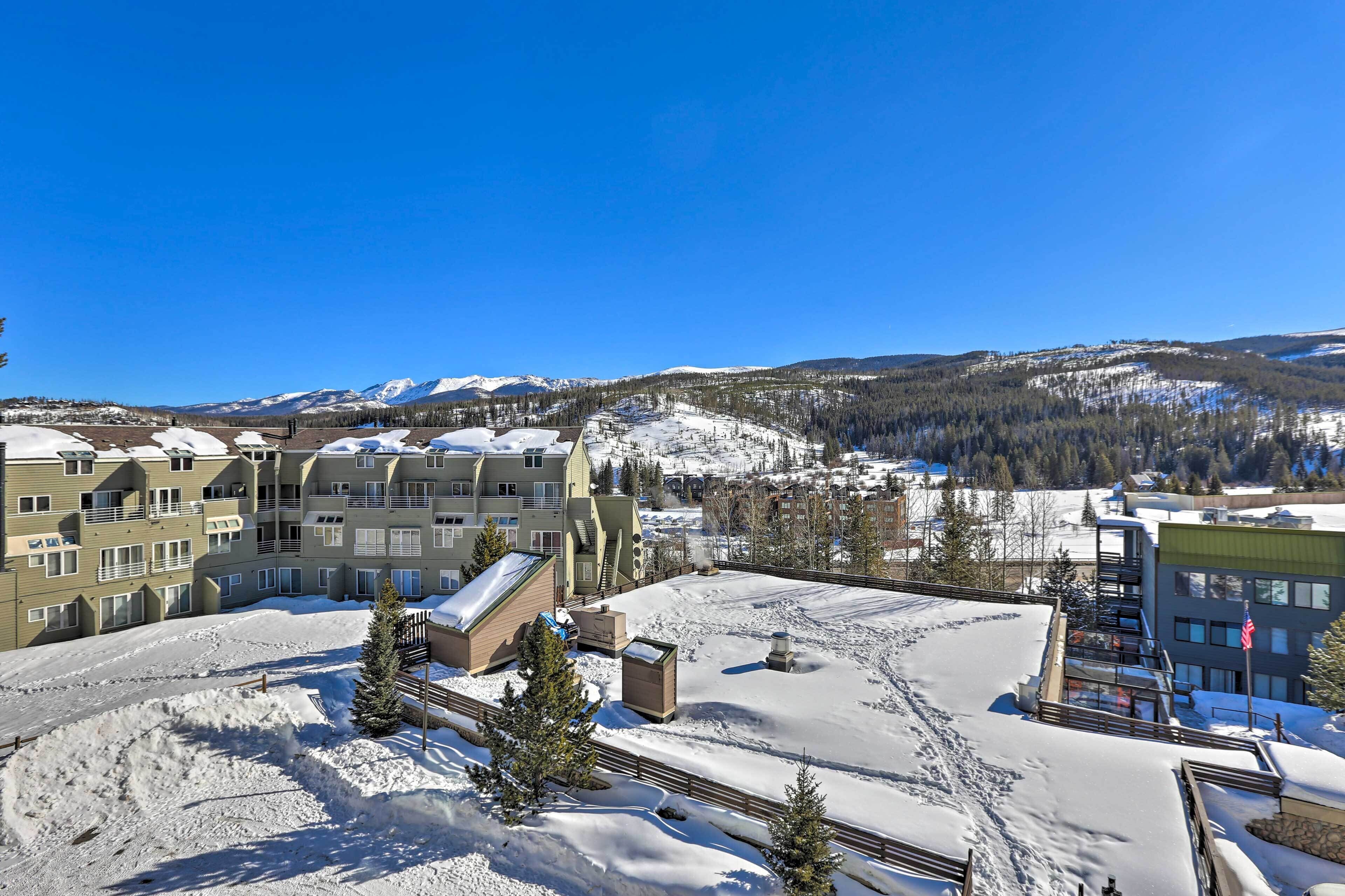 A snow-covered ski resort with buildings, a ski lift, and a mountain backdrop.