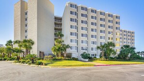 A multi-story hotel with a modern design, featuring balconies and a well-maintained garden with palm trees. - PCB Coastal Condo w/ On-site Beach Access! (Panama City Beach)